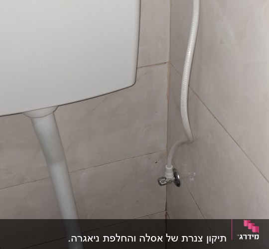 אסלה עם צינור מים מחובר לקיר